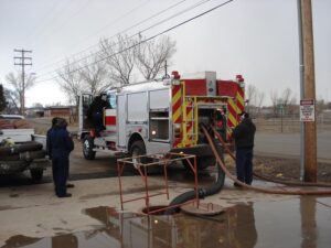 Two men in suits filling up the fire truck tanker